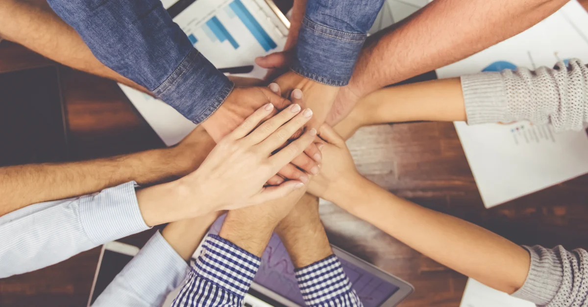 People's hands stack over each other symbolizing teamwork | Advivo