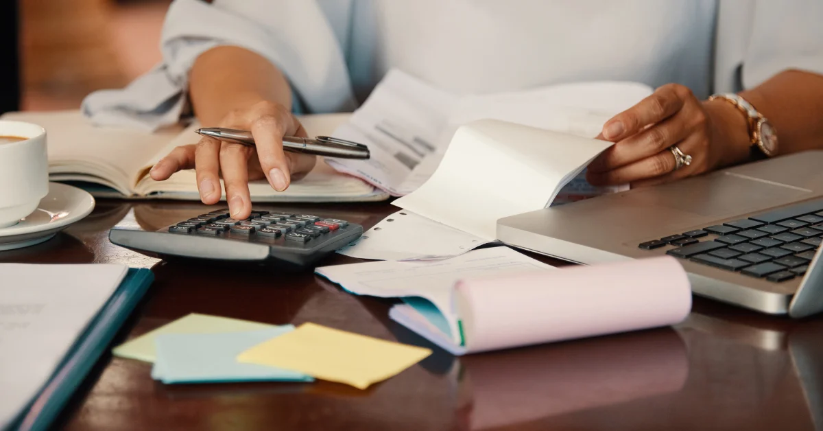Person using calculator while holding papers | Advivo